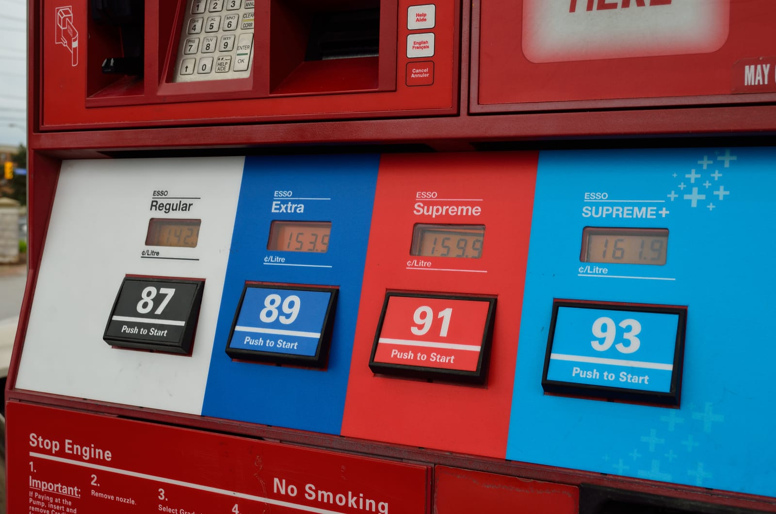 Surtidor de combustible en una gasolinera, con mangueras negras y amarillas.