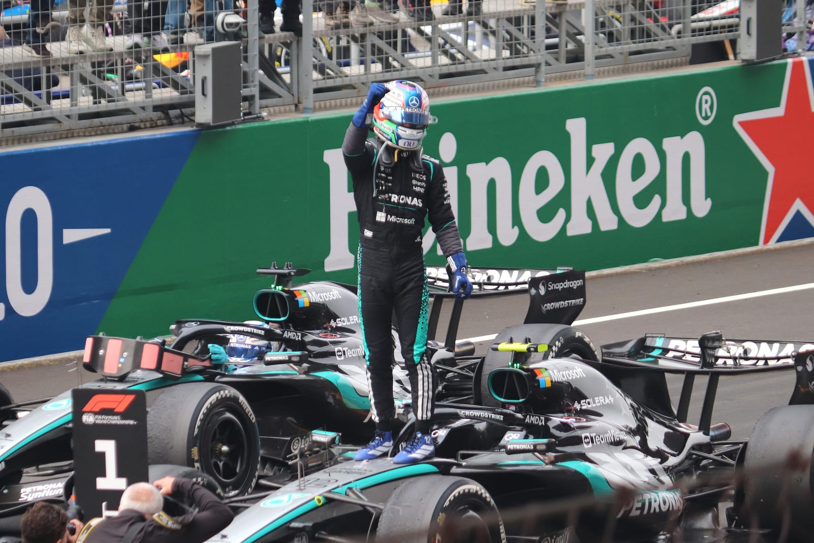 Kimi Antonelli, de pie sobre su Mercedes, celebra una victoria levantando el brazo ante la grada.