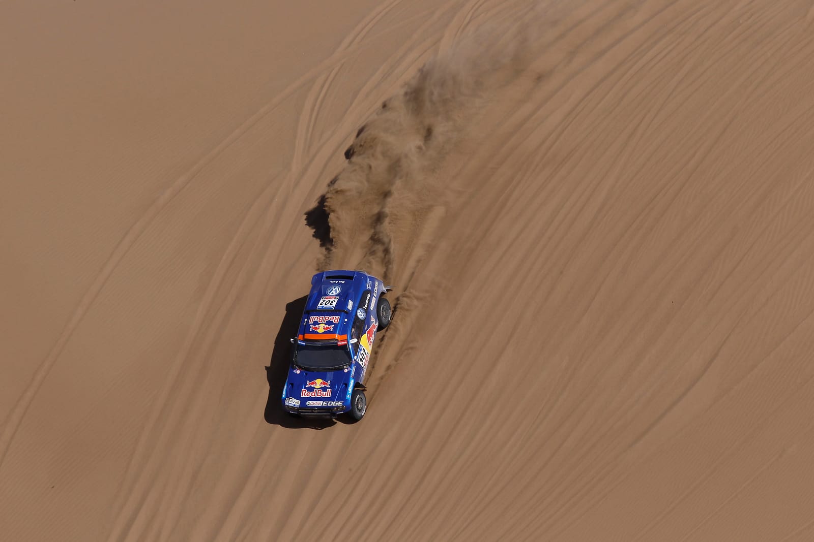 Un coche de rally atraviesa una duna durante una etapa del Dakar.