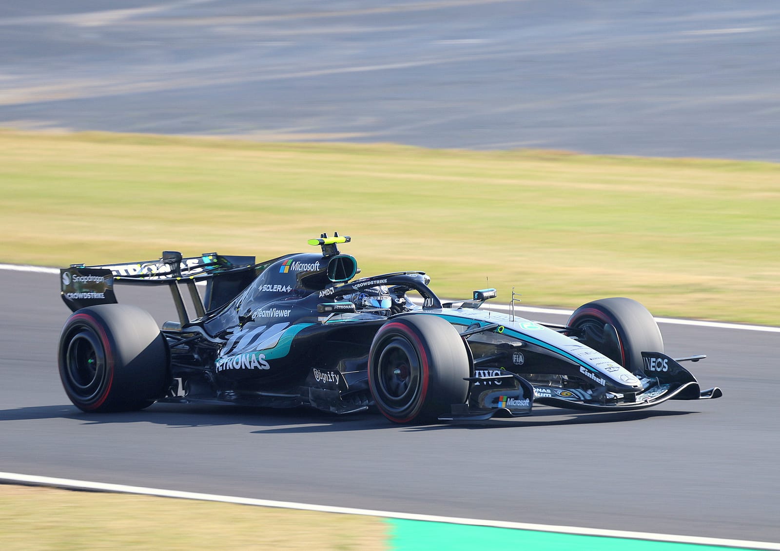 Monoplaza negro y plateado del Mercedes W17 de Kimi Antonelli tomando una curva en un circuito, con neumáticos de banda roja y movimiento de fondo.