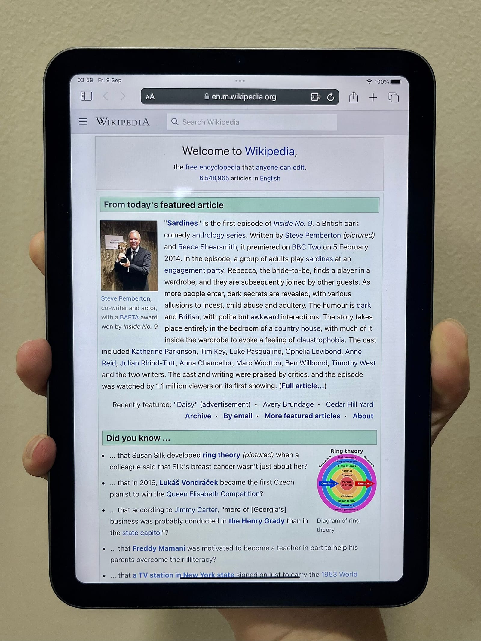 Un iPad mini de sexta generación sostenido con una mano y mostrando una página de Wikipedia.