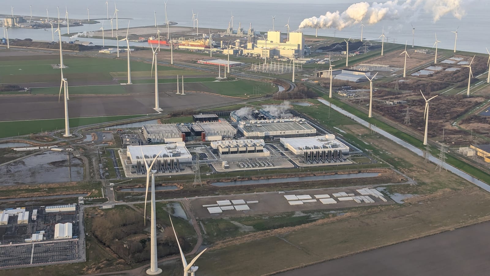 Vista aérea de un gran centro de datos de Google rodeado de aerogeneradores en una llanura.