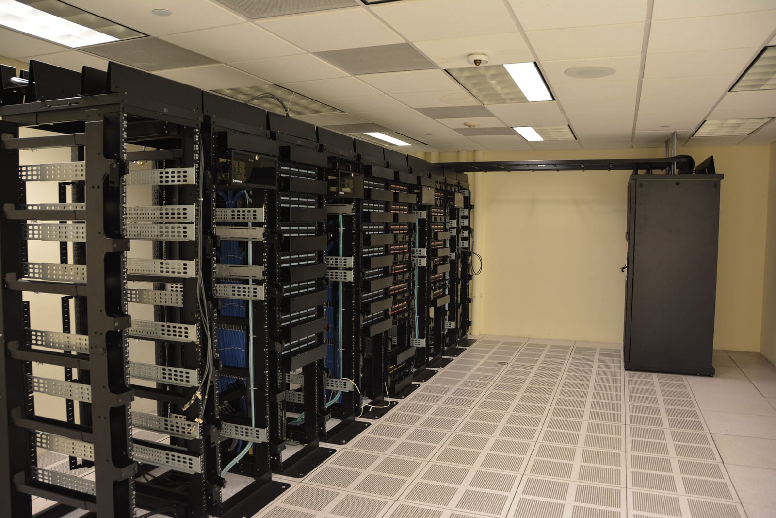 Pasillo de un centro de datos con armarios de servidores negros alineados.