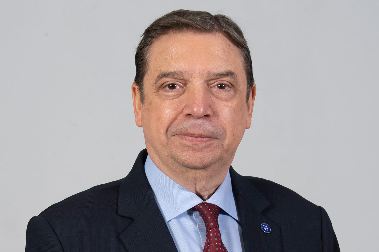 Retrato oficial de Luis Planas, ministro de Agricultura, Pesca y Alimentación, con traje oscuro, camisa azul y corbata granate sobre fondo gris.