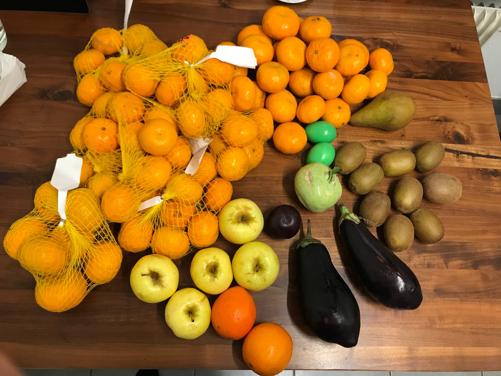 Mandarinas, manzanas, kiwis, berenjenas y otras frutas y verduras comestibles recuperadas del contenedor de un comercio, sobre una mesa de madera.
